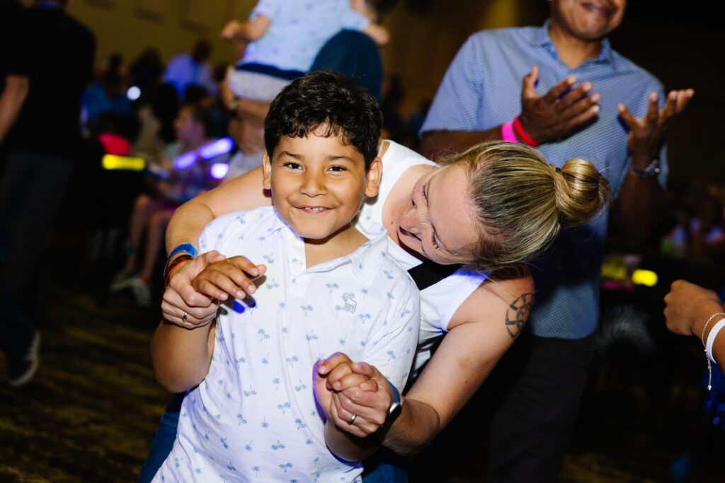 a mom has her arms wrapped around her son with Angelman syndrome