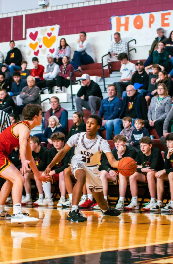 basketball player dribbling past opposing team member with crowd looking on